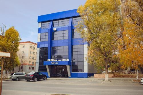 un edificio azul con coches estacionados frente a él en Hotel Astoria, en Volgograd