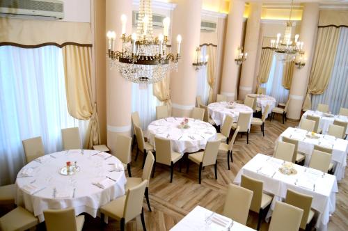 a restaurant with white tables and chairs and a chandelier at Grand Hotel Vittoria in Montecatini Terme