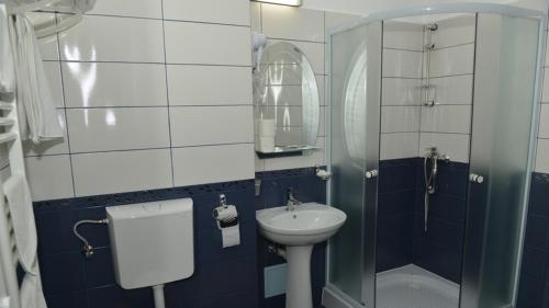 a bathroom with a sink and a toilet and a mirror at Hotel Corneliuss in Galaţi