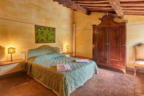 Un dormitorio con una cama y un armario de madera. en Casale il Gualdo by VacaVilla, en Radda in Chianti