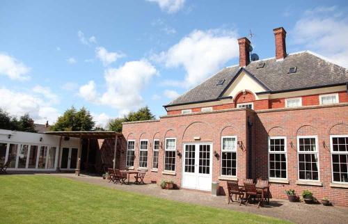 a large red brick building with a grass yard at Deincourt Hotel in Newark upon Trent
