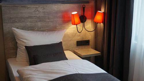 a bedroom with a bed with two lamps on it at Urban Home Hotel in Hamburg