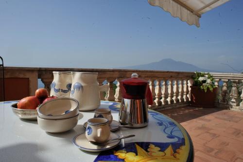 uma mesa com panelas de chá e frutas numa varanda em Villa Margi em Vico Equense