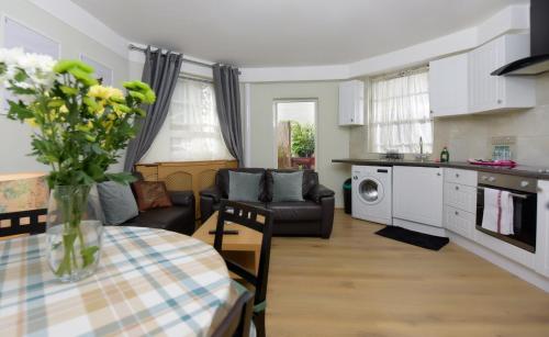 eine Küche und ein Wohnzimmer mit einem Tisch und einem Sofa in der Unterkunft Gloucester Gardens in London