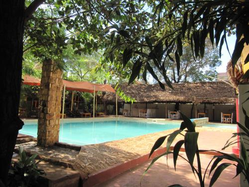 a swimming pool at a resort with a tree at Le Village Diego in Diego Suarez