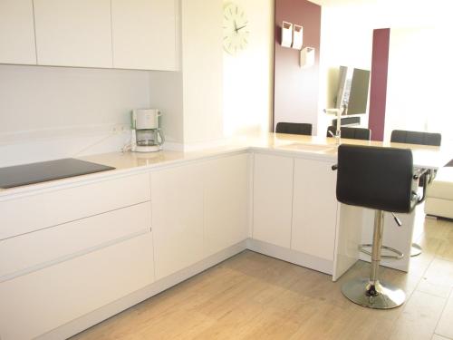 a kitchen with white cabinets and a black chair at Bella Vista First Class in Blankenberge