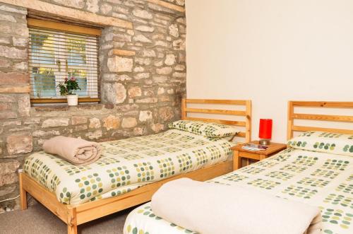 1 Schlafzimmer mit 2 Betten und einer Steinmauer in der Unterkunft Aqueduct Cottage in Llanover