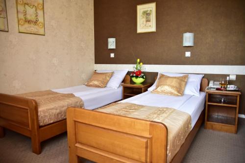 a hotel room with two beds and two tables at Garni Hotel Lav in Belgrade