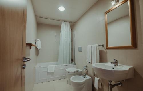 a white bathroom with a sink and a toilet at Hotel Albergaria Senhora do Espinheiro in Seia