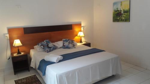 a bedroom with a large white bed with a wooden headboard at Giuseppe Suites Hotel in Asuncion