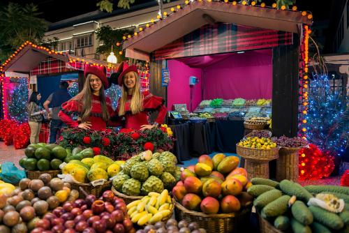 two women standing in front of a market with fruits and vegetables at Jardins Piornais Funchal Apartment in Funchal