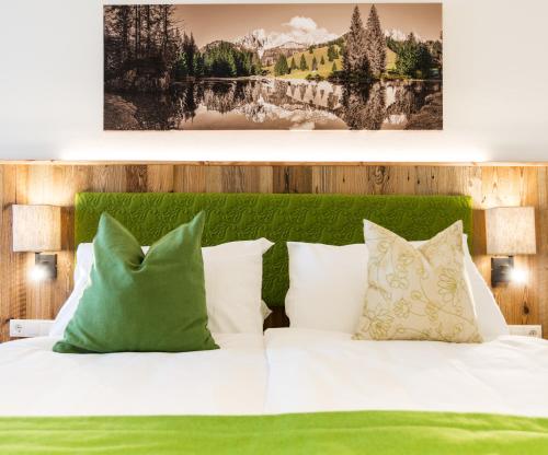 a bedroom with a bed with green and white pillows at Alpenhotel Wurzer in Filzmoos