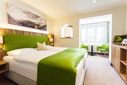 a bedroom with a large bed with a green headboard at Alpenhotel Wurzer in Filzmoos
