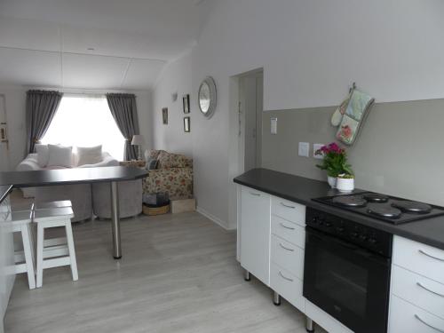 a kitchen and living room with a stove top oven at Rose and Ale Self Catering Units in Gonubie