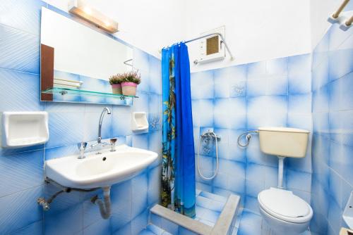 a blue tiled bathroom with a toilet and a sink at Kavos Fantasia Complex in Kavos