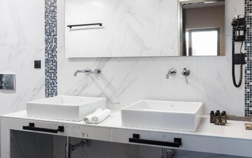 a white bathroom with two sinks and a mirror at 360Degrees Pop Art Hotel in Athens