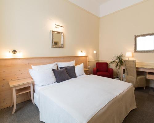 1 dormitorio con 1 cama blanca grande y escritorio en Unitas Hotel en Praga