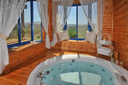 a bath tub in a room with windows at Meshi Belavan in Metulla