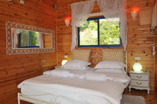 two beds in a wooden room with two windows at Meshi Belavan in Metulla