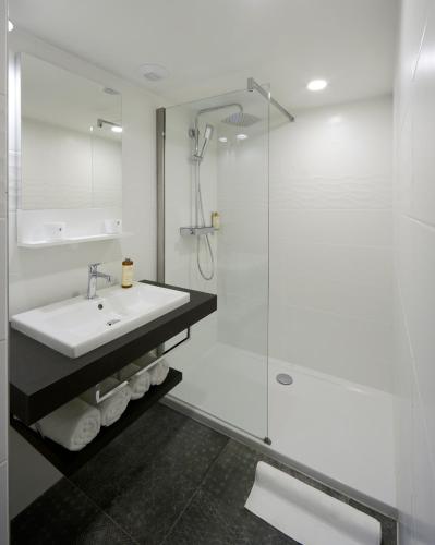 a white bathroom with a sink and a shower at Les Maisons du Pont - Charme & Caractère in Aubusson
