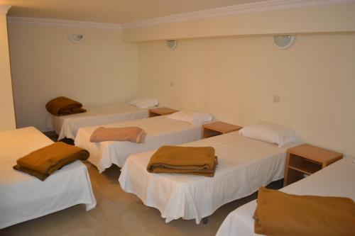 a room with four beds with brown blankets on them at Arenilha Guest House in Vila Real de Santo António