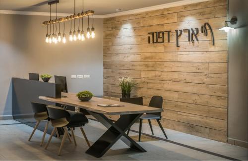 a dining room with a wooden wall with a table and chairs at Erettz Dafna Travel Hotel in Dafna