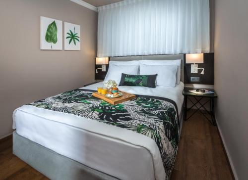 a bedroom with a large bed with a tray of food on it at Erettz Dafna Travel Hotel in Metsudat Menahem Ussishkin Alef