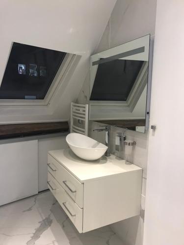 une salle de bain blanche avec un lavabo et un miroir dans l'établissement Appartements Haussman Lafayettes, à Paris