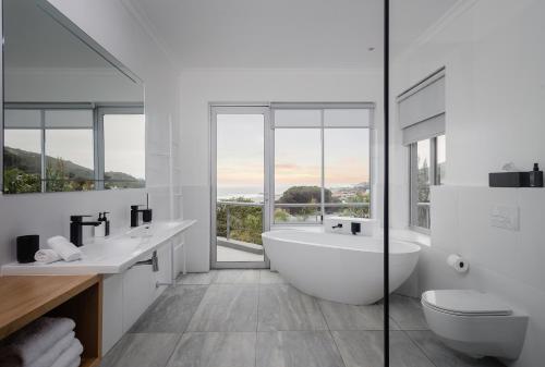 La salle de bains blanche est pourvue d'une baignoire et de deux lavabos. dans l'établissement Sovn Experience+Lifestyle, au Cap