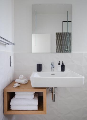 a white bathroom with a sink and towels at Sovn Boutique Hotel in Cape Town