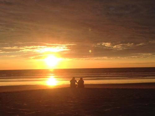 two people sitting on the beach watching the sunset at Sapa Inka in Montañita