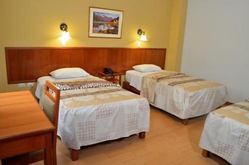 a room with three beds and a table at Primavera Plaza Hotel in Tacna