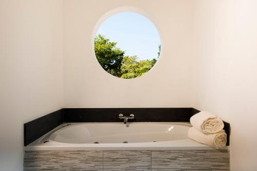 a bathroom with a bath tub with a round mirror at Emotions by Hodelpa Puerto Plata in San Felipe de Puerto Plata