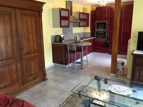 une cuisine avec des placards rouges et une table en verre dans l'établissement les menetriers, à Ribeauvillé