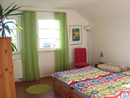 een slaapkamer met 2 bedden en een rode stoel bij Haus Köberle Ummendorf in Biberach-Ummendorf
