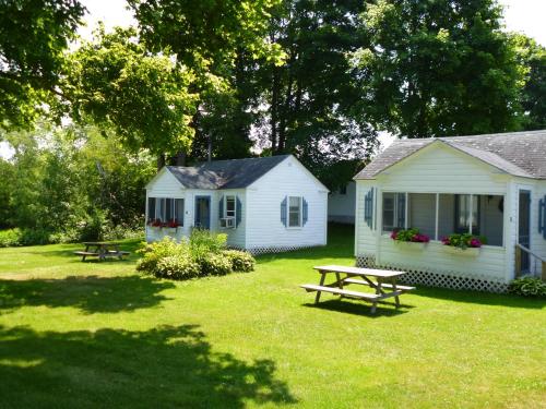 a house sitting in the middle of a lush green field at Bar Harbor Cottages & Suites in Bar Harbor