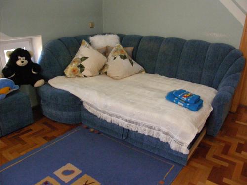 a blue couch with a stuffed animal sitting on it at Home for Guests Lakštingala in Šiauliai