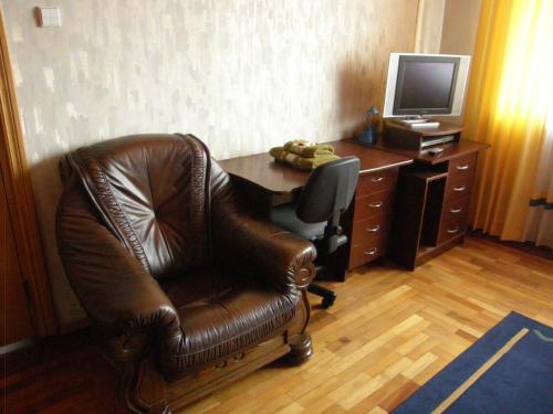 a leather chair and desk with a computer and a television at Home for Guests Lakštingala in Šiauliai