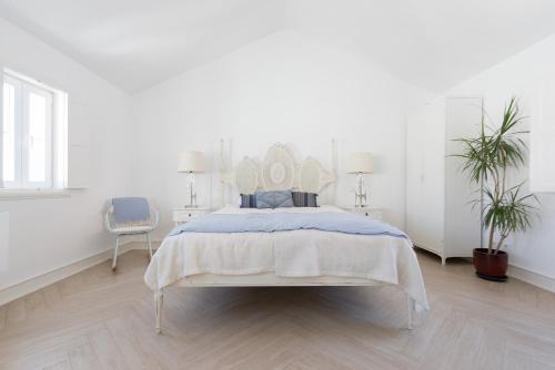 a white bedroom with a bed and a chair at Almamater Lisbon Apartments in Lisbon