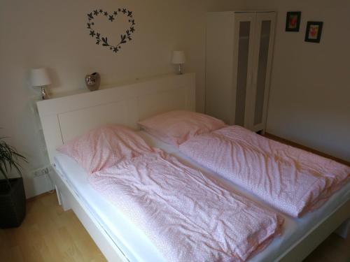 an unmade bed with pink sheets on top of it at Köln Appartement in Cologne