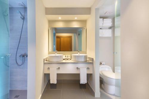 a bathroom with two sinks and a toilet and a mirror at Emotions by Hodelpa - Juan Dolio in Juan Dolio