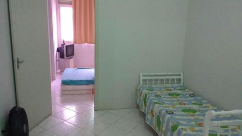 een slaapkamer met een bed en een kamer met een televisie bij Apartamento Praia da Costa in Vila Velha