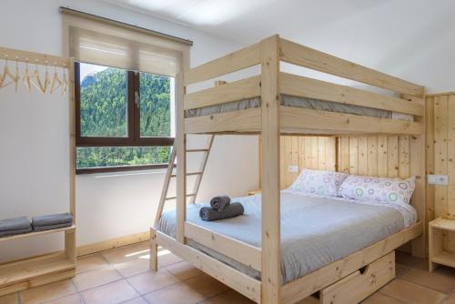 a wooden bunk bed in a room with a ladder at Camping Selva de Oza in Hecho