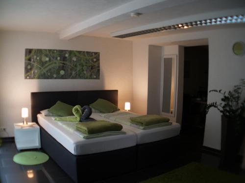 ein Schlafzimmer mit einem großen Bett mit zwei grünen Kissen in der Unterkunft Gästeappartement Viktoria in Sinsheim