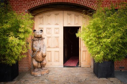 Una statua di un orso che si trova davanti a una porta di Crazy Bear Beaconsfield a Beaconsfield