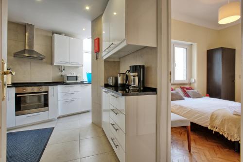 a kitchen with white cabinets and a bed in a room at Almirante Top Floor / Almirante Reis Avenue in Lisbon