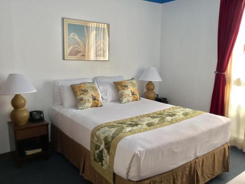 a bedroom with a large bed with two lamps at Holiday Surf Hotel (with full kitchen) in Honolulu