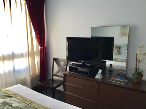 a bedroom with a television on a dresser with a bed at Holiday Surf Hotel (with full kitchen) in Honolulu