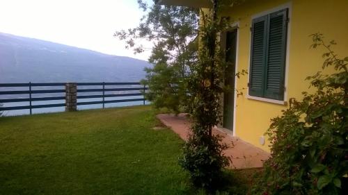 a yellow house with a window and a green shutter at CASA NAVLA' AppartamentI "Ulivi"- "Fiori" -"Velieri"-"Luna"-"Nido"-"Taverna" in Tignale