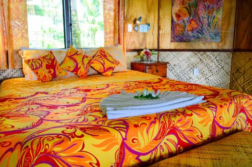 a large bed with a colorful blanket on it at Le Vasa Resort in Fuailalo